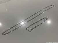 Full view of .925 sterling silver chain necklace and bracelet laid flat on surface showing overall lengths and chain styles