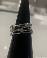 Front view of sterling silver twisted band ring with cubic zirconia stones displayed on ring stand.