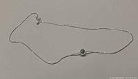 Sterling silver snake chain necklace laid out on a flat surface, showing the pendant and chain length.