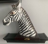 Front-left side view of the zebra figure on wooden base showing detailed zebra stripes and brass nameplate.