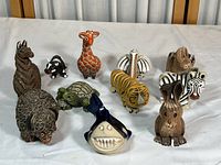 Full view of the collection showing all 11 clay animal figurines arranged on white surface.