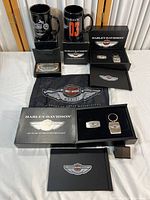 Full view of the Harley-Davidson 100th-anniversary collection including mugs, keychain, belt buckle, flag, and boxes