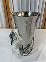 Photo of 10-inch tall hammered metal vase with twisted vine detail and tag attached