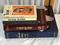 Stack of five books, showing front covers and spines. Visible wear on paperbacks and hardcovers.