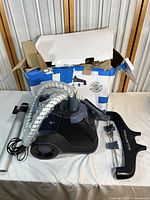 Photo of Rowenta garment steamer unit and accessories on cloth surface with original box behind, showing product and condition