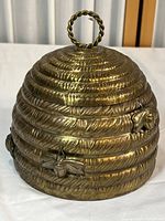 Closed view of vintage brass beehive honey pot with bee decorations and loop handle on lid