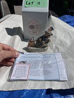Figurine with box and information card held by hand, showing the full item and documentation