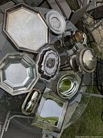 Photo of entire lot on glass table outdoors showing all nine silver-plated serveware pieces.