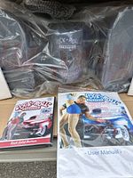 Photo of sealed Rock 'n Roll Stepper exercise equipment in original plastic packaging with booklets visible
