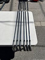 Six right-handed Nike Ignite steel irons laid on a white table showing full club length and grips.