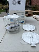 Photo of glass carafe, white lid, and packaging box showing condition and included pieces