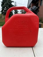Front view of red gasoline container showing safety warnings and 5L volume marking.