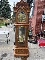 Full view of Ridgeway grandfather clock showing carved wood case and glass front with visible pendulum.