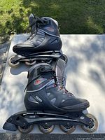 Side view of pair of inline skates showing gray and black boots with rollerblade branding, and four wheels on each skate with some light wear.