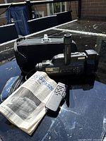 Photo of Sony CCD-FX520 camcorder, original remote, manual, and carrying case arranged on a reflective surface outdoors.