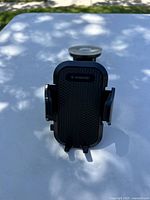 Front view of the black VANMASS car phone mount showing the adjustable phone holder with textured grip surface and branding.