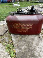 Front view of red Johnson Mile Master metal fuel tank showing faded branding and surface wear.