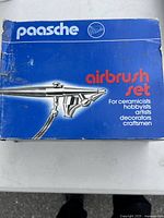Box with Paasche branding and airbrush image, labeled as airbrush set for ceramists, hobbyists, artists, decorators, and craftsmen.