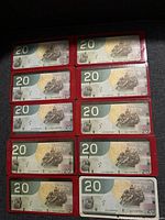 Top-down view of all ten notes in red protective sleeves, reverse side up.