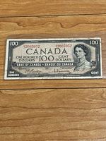 Front view of 1954 Canadian 100 Dollar banknote showing portrait, serial numbers, and signatures.