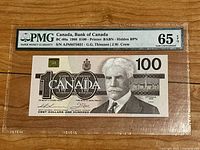 Encapsulated note obverse with PMG label showing grade 65 EPQ, front center on wood background