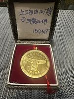 Front view of Chinese medallion in box showing bull/ox head design and Chinese characters.