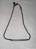 Full view of the older Pandora silver chain bracelet with a cubic zirconia bar centerpiece on a white surface.