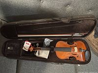 Full violin outfit in open case showing violin, bow, and accessories