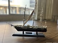 Left side view of the Flying Cloud clipper ship model showing sails, rigging, and wooden hull mounted on rectangular base with name plaque.
