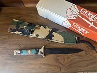 Knife, sheath, and original box on wooden surface