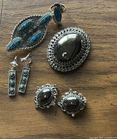 Photo showing entire lot of vintage hematite and turquoise jewelry on wooden surface.