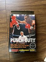 Front of Mike Tyson's Punch-Out!! NES game box showing iconic artwork of Mike Tyson in boxing pose, referee, and promotional text.