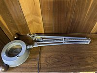 Full view of the lamp showing its spring-loaded double arm, clamp base, and circular magnifier with light housing.