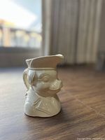 Front view of vintage pig toby creamer showing pig's face, hat spout and handle