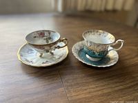 Photo showing the two teacup and saucer sets side by side on wooden table