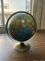 Front view of vintage globe showing continents including Africa, Europe, and Asia with blue oceans and vintage color scheme.