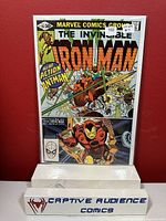 Photo of The Invincible Iron Man comic book #151 from Marvel Comics Group, showing front cover with Iron Man and Ant-Man, in protective sleeve with a stand labeled 'Captive Audience Comics'.