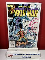 Photo shows Iron Man #176 comic book with colorful cover art and price sticker, displayed upright on a white stand labeled Captive Audience Comics.