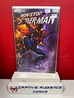 Plastic sleeve protected Non-Stop Spider-Man #1 comic with fiery and purple background cover art, featuring Spider-Man in mid-air pose, displayed on stand with Captive Audience Comics sign.