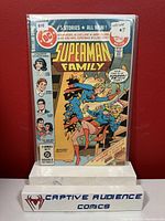 Photo of the Superman Family #215 comic book in protective sleeve on a white stand with red background