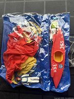 View of entire set inside original blue transparent plastic bag showing kayak, parachute, and action figure.