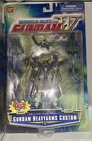 Front view of sealed Gundam Wing Heavyarms Custom figure on original card packaging, showing figure and accessories.