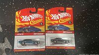 Two 2014 Hot Wheels Classics Series 1 1967 Camaro die-cast cars in sealed packaging, showing front of package and cars.