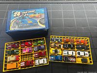 Blue carrying case labelled '24 Car Case' with 23 loose toy cars stored in two yellow plastic trays.