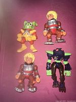 Four Buck O'Hare action figures arranged on a pink surface, showing the front of all figures.