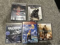 Five PlayStation game cases laid out on carpet: Diablo III, Call of Duty Advanced Warfare, Call of Duty Ghosts, Final Fantasy X (PS2), Call of Duty Modern Warfare 2