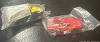 Photo of two sealed Hot Wheels promotional cars in their original sealed clear plastic bags, one is a red car labeled Hormel Chili and the other is a 4x4 truck.