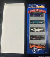 Overall view of Special Edition Hot Wheels cars in original General Mills blue box with clear display window and separate white shipping box.