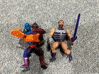 Photo showing Two-Head and Fisto action figures, Two-Head has blue and purple colors with orange armor and shield; Fisto has grey and purple armor with a sword.