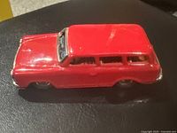 Side view of red vintage tin wagon toy showing glossy red sides and window lithograph details.